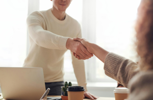 Man and woman shake hands at desk.